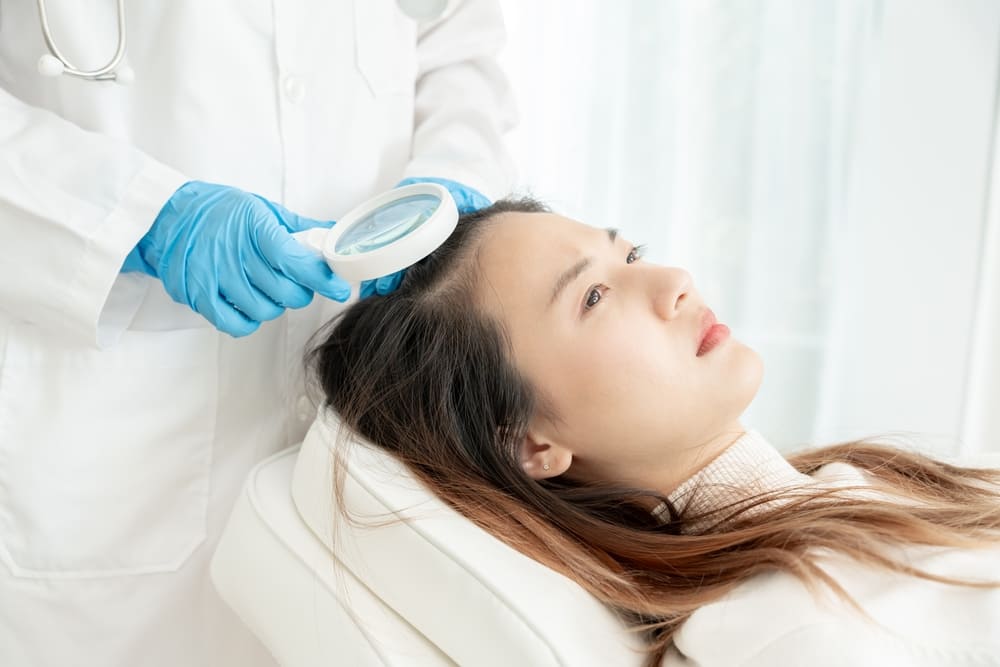 A doctor checks the hair of an Asian woman. Asian hair transplants have some nuances.
