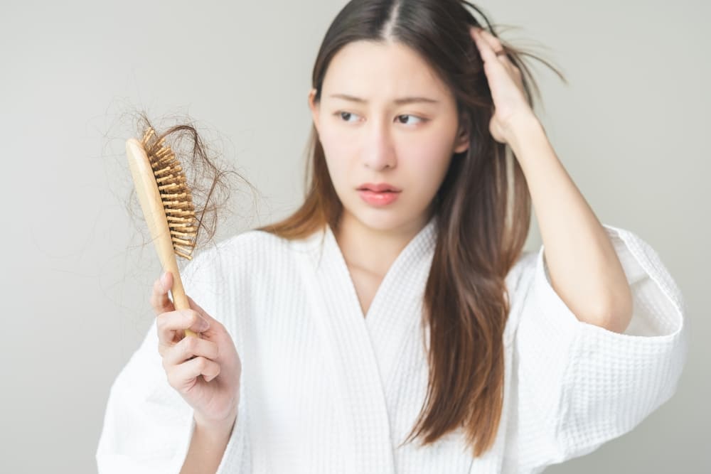 A young Asian woman faces hair loss. Fortunately, there are natural home remedies for hair fall.