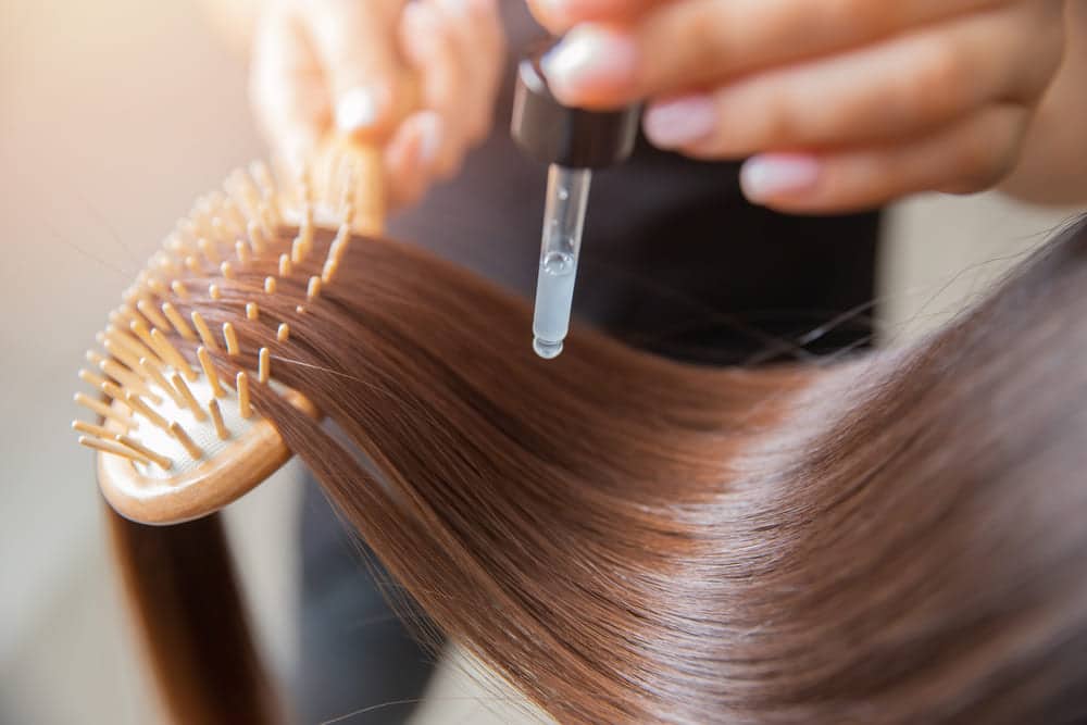 Aloe vera drops being applied to hair. This is one of the natural home remedies for hair fall.