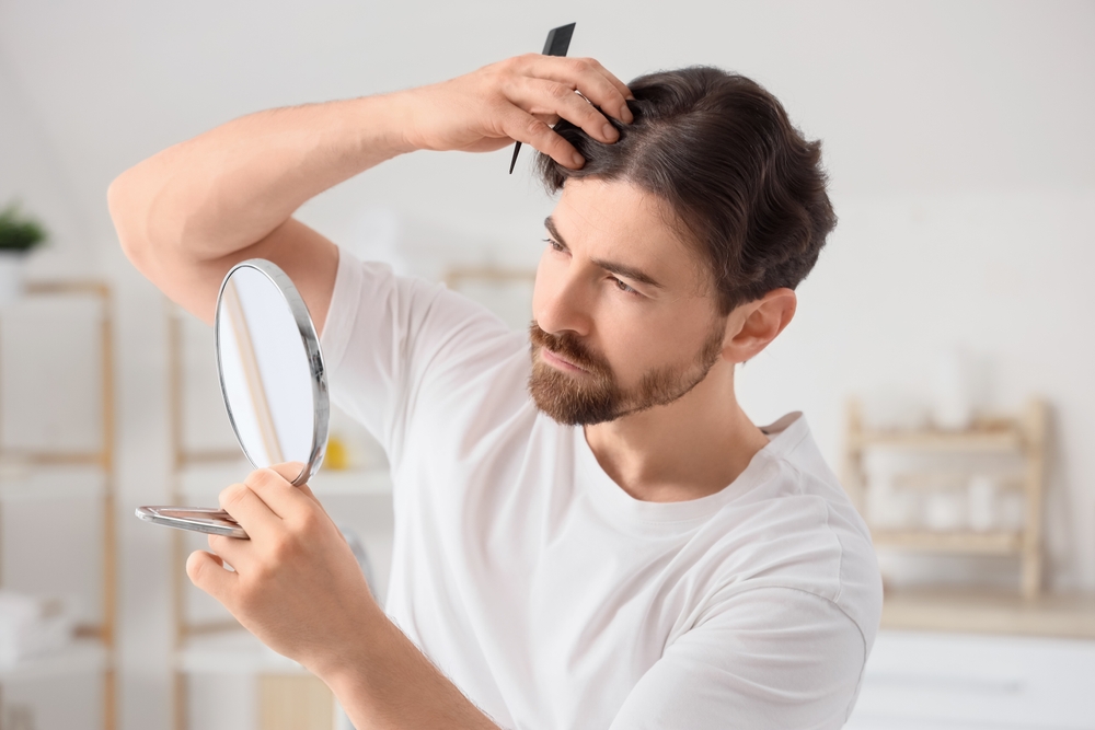 A man checks his hair in the mirror. Dutasteride or finasteride may be administered for hair loss.
