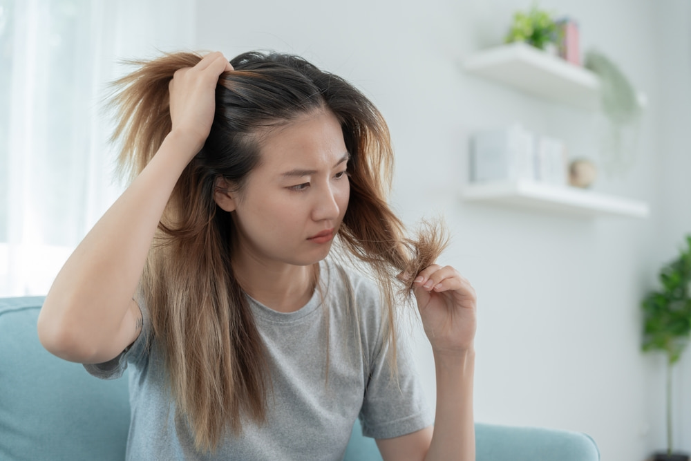 A young woman checking her hair for improvements in female hair loss after pregnancy